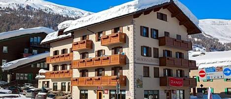 Un hotel de varios pisos con balcones, un bar y un letrero que indica un complejo de esquí.