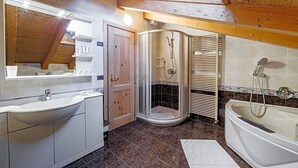 A bathroom with a sink, shower, and bathtub, wooden ceiling beams, and a tiled floor. - Hotel San Rocco (Livigno)