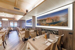 Un restaurante con interiores de madera, varias mesas para comer y grandes pinturas de paisajes en las paredes.
