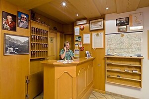Un mostrador de recepción con encimera de madera, fotografías enmarcadas, un mapa y varios avisos en la pared.