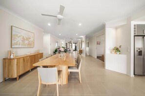 A spacious kitchen with a large island, modern appliances, and a view into the dining area. - Waters Edge Twin Waters - Pool, Deck & Kayaks (Coolum Region)