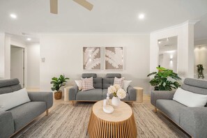 A modern living room with grey sofas, a wooden coffee table, and decorative wall art. - Waters Edge Twin Waters - Pool, Deck & Kayaks (Coolum Region)