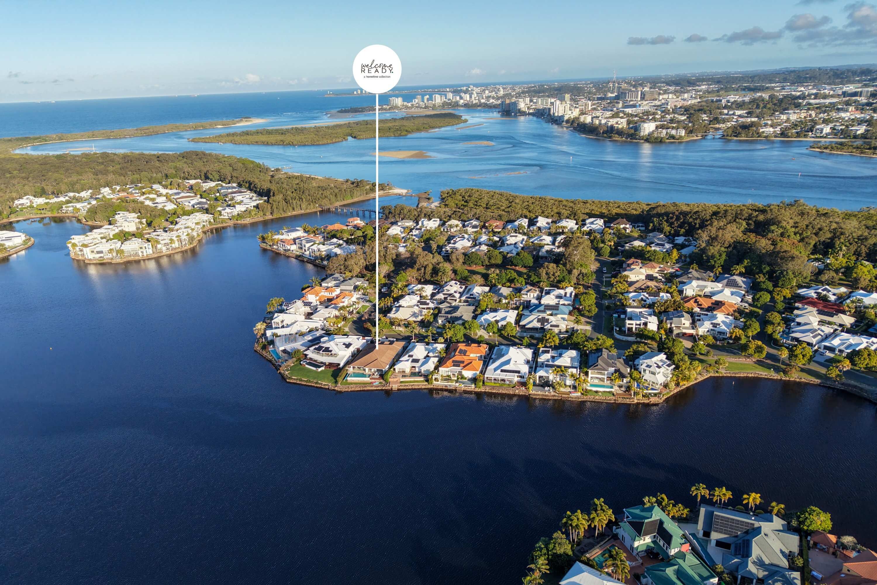 Luchtbeeld van een kustgebied met woningen, een jachthaven en een bord waarop 'welcome READY' staat.