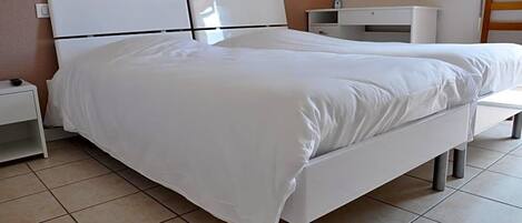A single-bed room with a white headboard, a bedside table, and a nightstand.