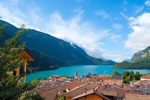 Uma cidade com arquitetura tradicional, um lago e montanhas ao fundo.