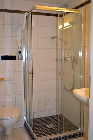 A bathroom with a glass-enclosed shower, a white toilet, and a sink. - Aparthotel Sprendlingen (Sprendlingen)