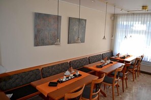 A dining area with long tables, benches, and hanging pendant lights. - Aparthotel Sprendlingen (Sprendlingen)