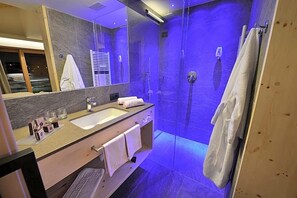 Un baño moderno con ducha envuelta en vidrio, tocador con lavabo y espejo.