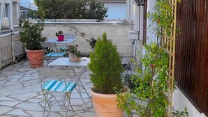 Eine Terrasse mit Tisch und Stühlen, Blumentöpfen und einem Holenzaun.