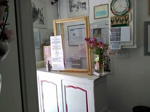 A reception desk with a framed notice, a clock, and a bulletin board with various notices. - Le Parisien (Saintes)
