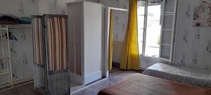 Um quarto com uma cama, um guarda-roupa e uma janela com cortinas.