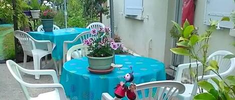 An outdoor patio area with tables and chairs, potted plants, and a small garden.