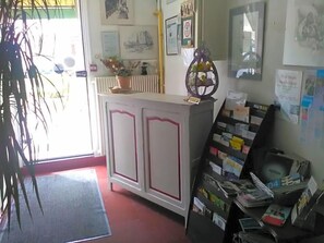 Uma área de recepção com balcão, um mural com diversos avisos e uma porta que dá para o exterior.