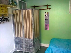A room with a striped wardrobe, a bed with a blue cover, and a wall-mounted mirror. - Le Parisien (Saintes)