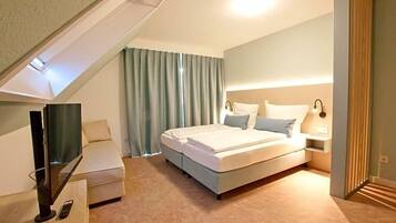 Un dormitorio moderno con cama, mesita de noche, lámpara y televisión.