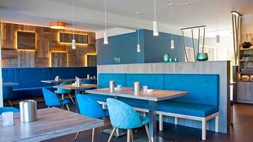 Un comedor moderno con paneles de madera en la pared, asientos azules e iluminación colgante.