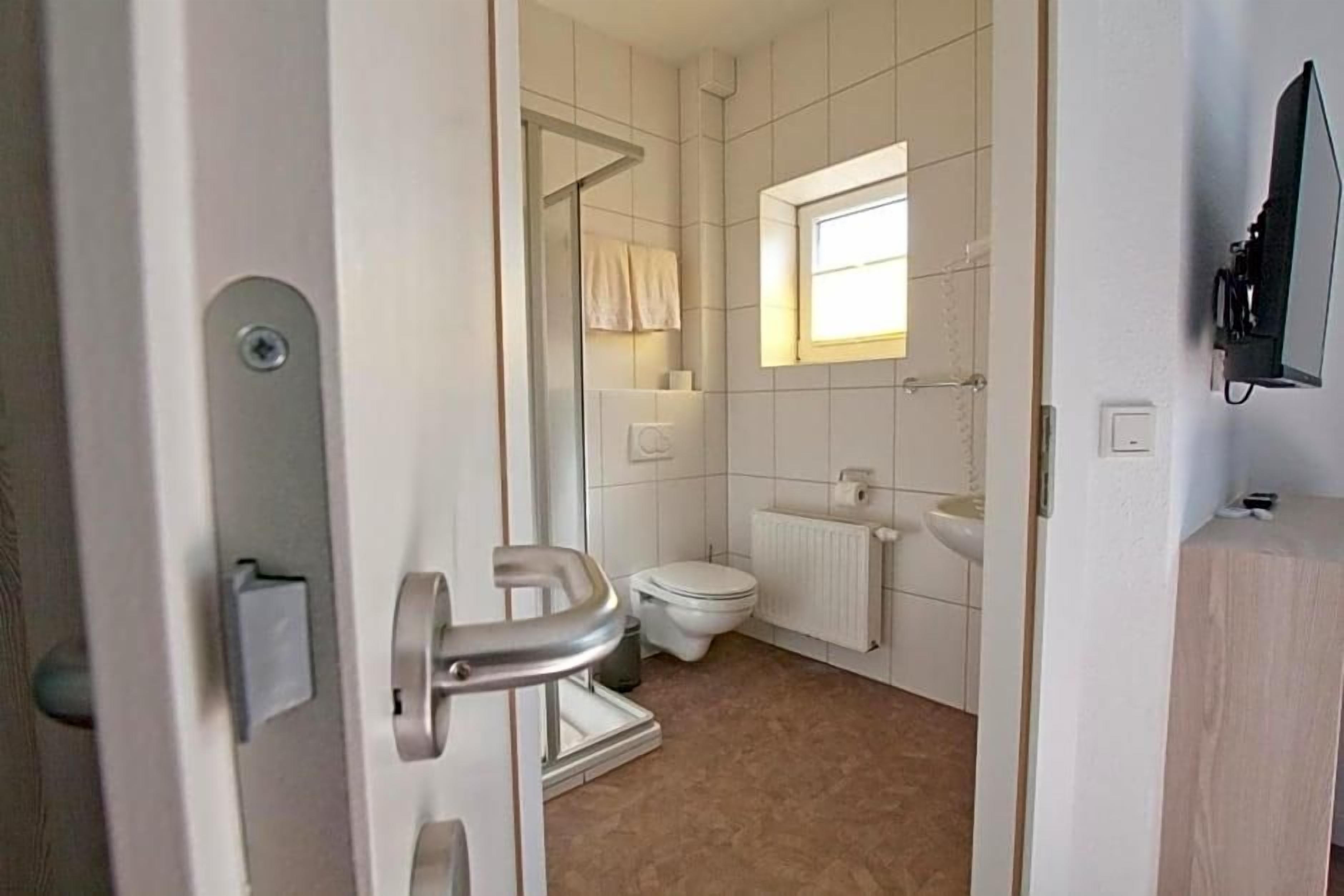 Un baño con inodoro, lavamanos, ventana y zona de ducha.