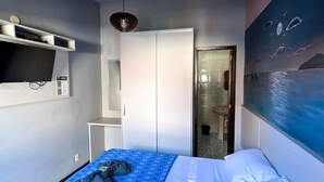 Une chambre à coucher avec un lit, une armoire, un téléviseur et un tableau accroché au mur.