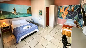 Une chambre d’hôtel avec un lit, un bureau, une chaise, une télévision et une grande fresque murale.