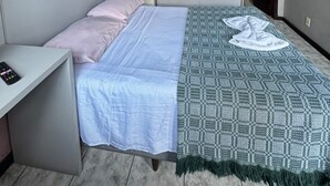 Une chambre à coucher comprenant un lit, une table de chevet, une armoire, un tableau et un luminaire suspendu.