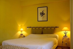 A bedroom with a bed, two bedside tables with lamps, a headboard, and a framed picture on the wall. - Le Provenvßal (Aups)