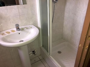 A bathroom with a white pedestal sink, a glass shower enclosure, and a tiled floor. - Le Provenvßal (Aups)