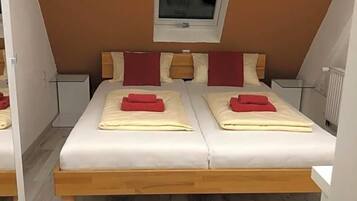 A bedroom with two beds, a window, and a radiator.