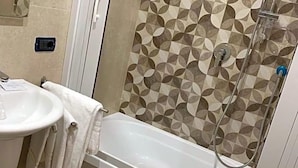 Un baño con ducha, lavabo y toallero.