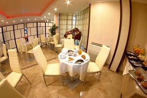 Un comedor con mesas redondas, sillas y alimentos para el desayuno.