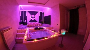 Una habitación con una zona de estar central, un radiador y una pequeña mesa con luz azul.