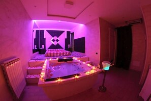 Una habitación con una zona de estar central, un radiador y una pequeña mesa con luz azul.
