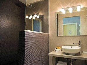 A bathroom with a large mirror, a sink, and a shower. - Hotel Parco (Cervia)