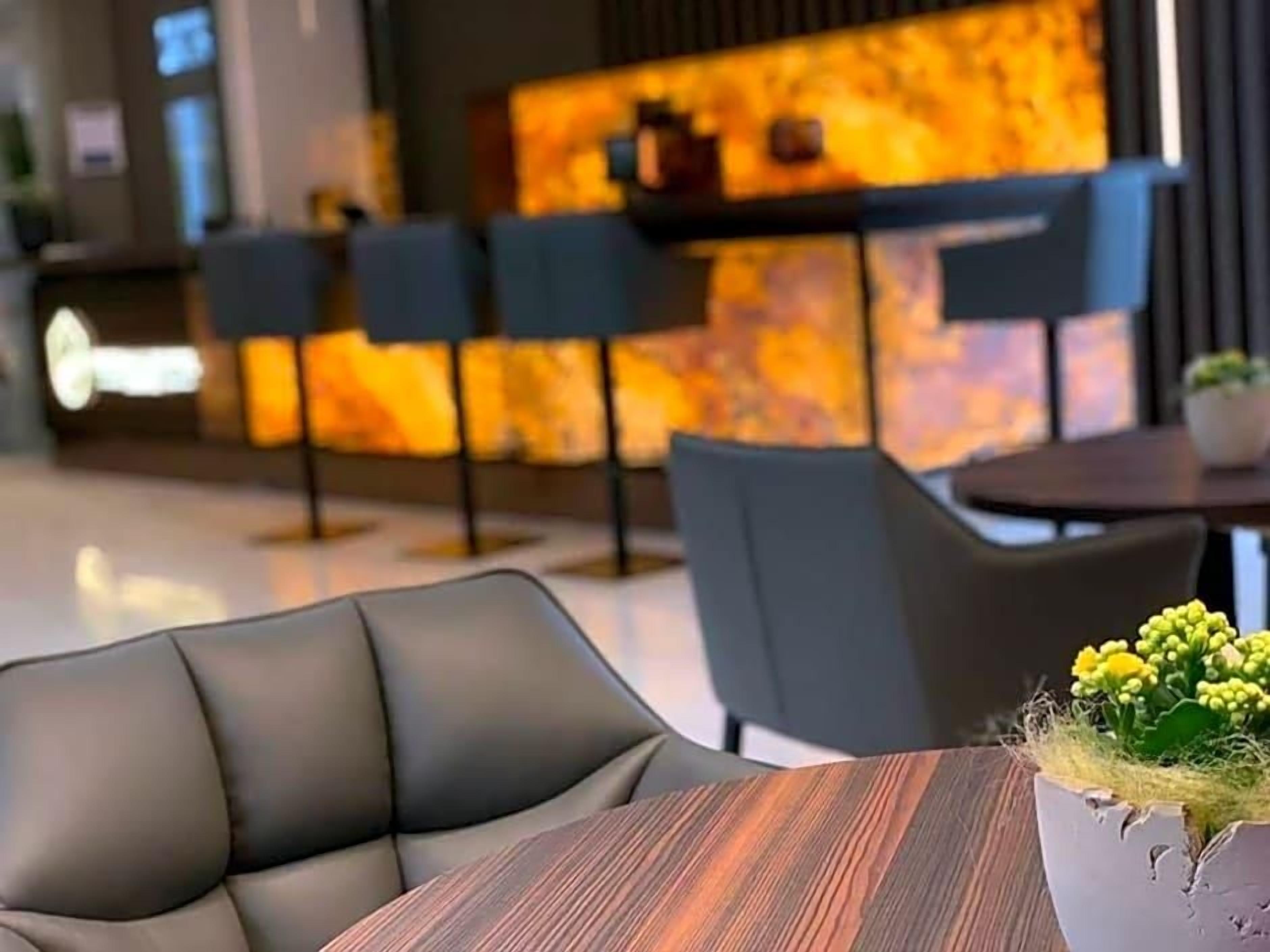 A modern hotel lobby with a reception desk, seating area, and a potted plant.