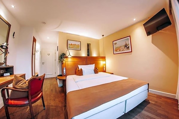 A hotel room with a bed, a desk, a chair, a mirror, and two wall-mounted lamps. - Hotel Zum Ochsen (Oberstenfeld)