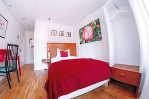 A bedroom with a wooden headboard, a red bedspread, a nightstand, and a wall-mounted picture of a rose. - Hotel Zum Ochsen (Oberstenfeld)