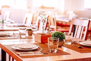 A dining table set with plates, cutlery, and a glass of water, with a small plant and a decorative item on the table.