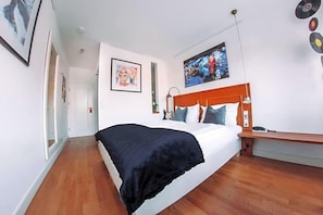 A bedroom with a bed, a bedside table, a lamp, and a wall with a poster. - Hotel Zum Ochsen (Oberstenfeld)