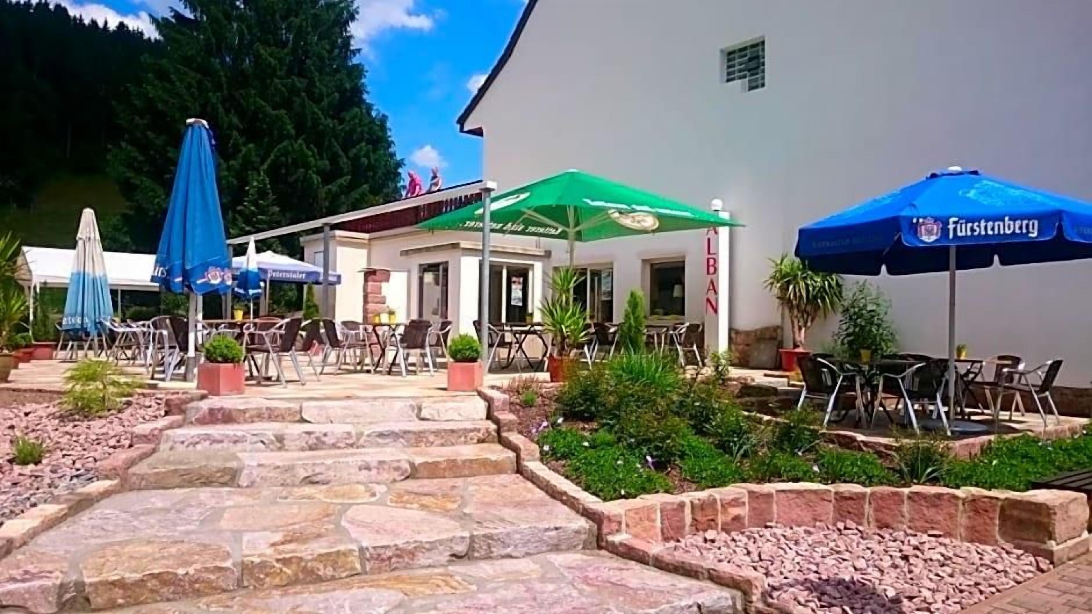 An outdoor seating area with tables and chairs, umbrellas, and a building with signage.