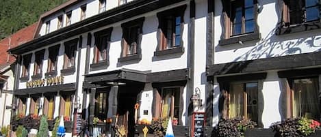 Un edificio tradicional con varios ventanales, terraza exterior y un letrero que indica un restaurante.