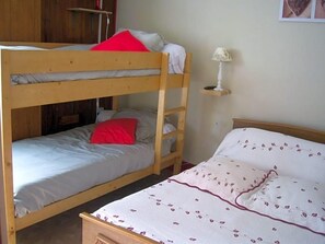 Uma cama box com beliche e uma cama de solteiro, ambas com travesseiros e cobertores.