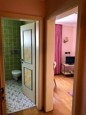 Et badeværelse med toilet, bruseområde og håndvask.