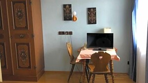Een kamer met een bed, een houten garderobe, een bureau met een computer en een stoel.