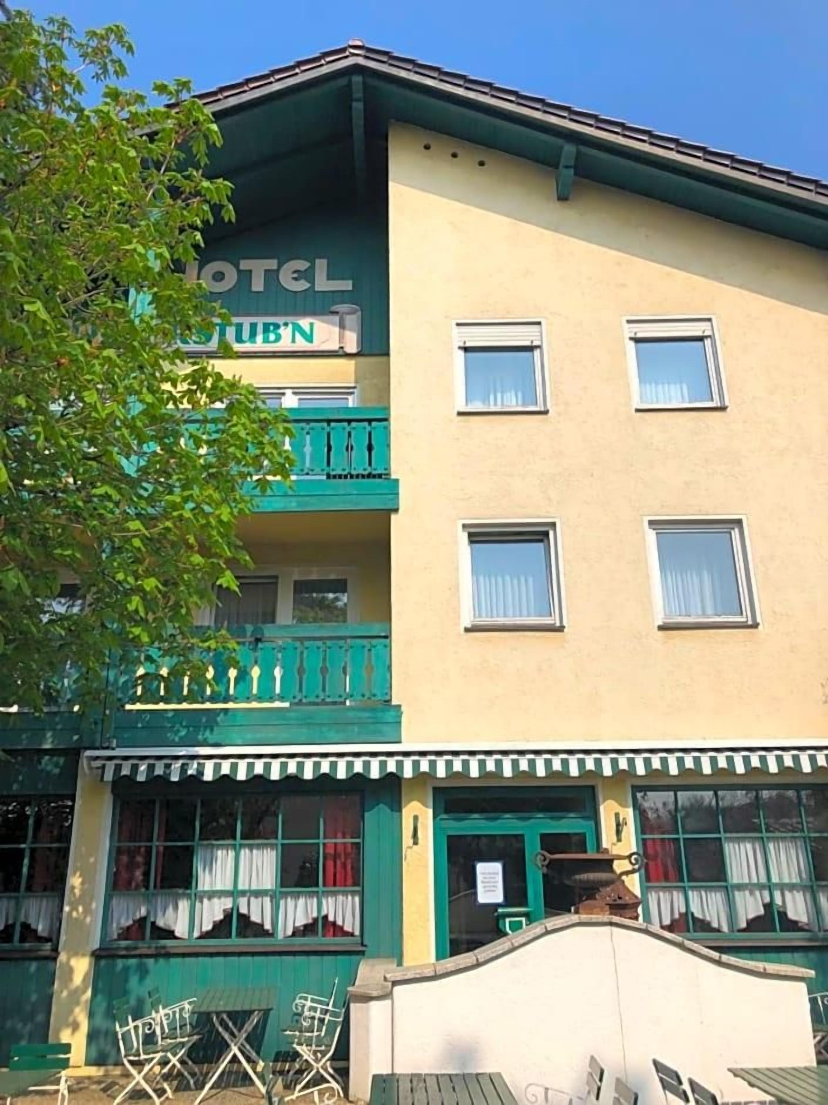 A two-story building with a sign reading 'HOTEL' and 'TUB'N'. There are windows on the second floor and a balcony with railings.