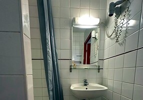 Un baño con un lavabo blanco, un espejo y un secador de pelo montado en la pared.