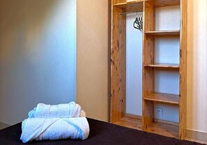 Una habitación con una cama, un armario de madera y una toalla doblada en el suelo.