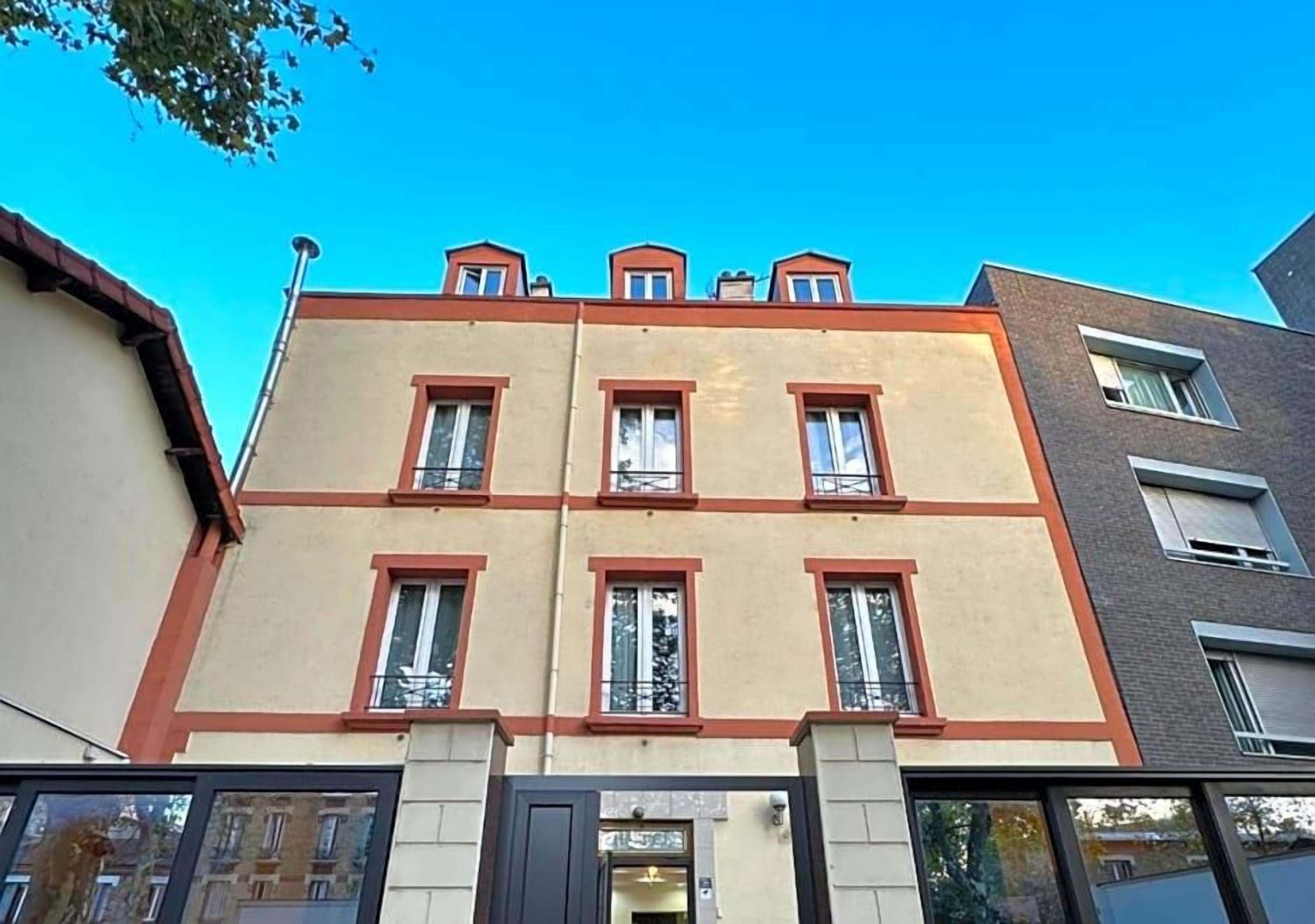 Un edificio de varios pisos con techo plano, ventanas amplias y una entrada visible.