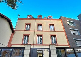 Un edificio de varios pisos con techo plano, ventanas amplias y una entrada visible.