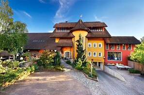 A traditional building with a central entrance, a covered outdoor seating area, and a flag on top. - Landhotel Krone (Heitersheim)
