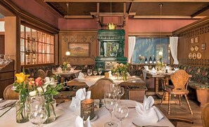 Un ristorante con diversi tavoli, sedie e un mobiletto decorativo verde.