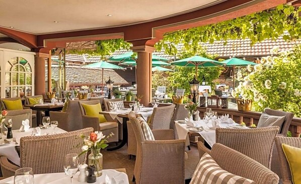 An outdoor dining area with wicker furniture and green umbrellas. - Landhotel Krone (Heitersheim)